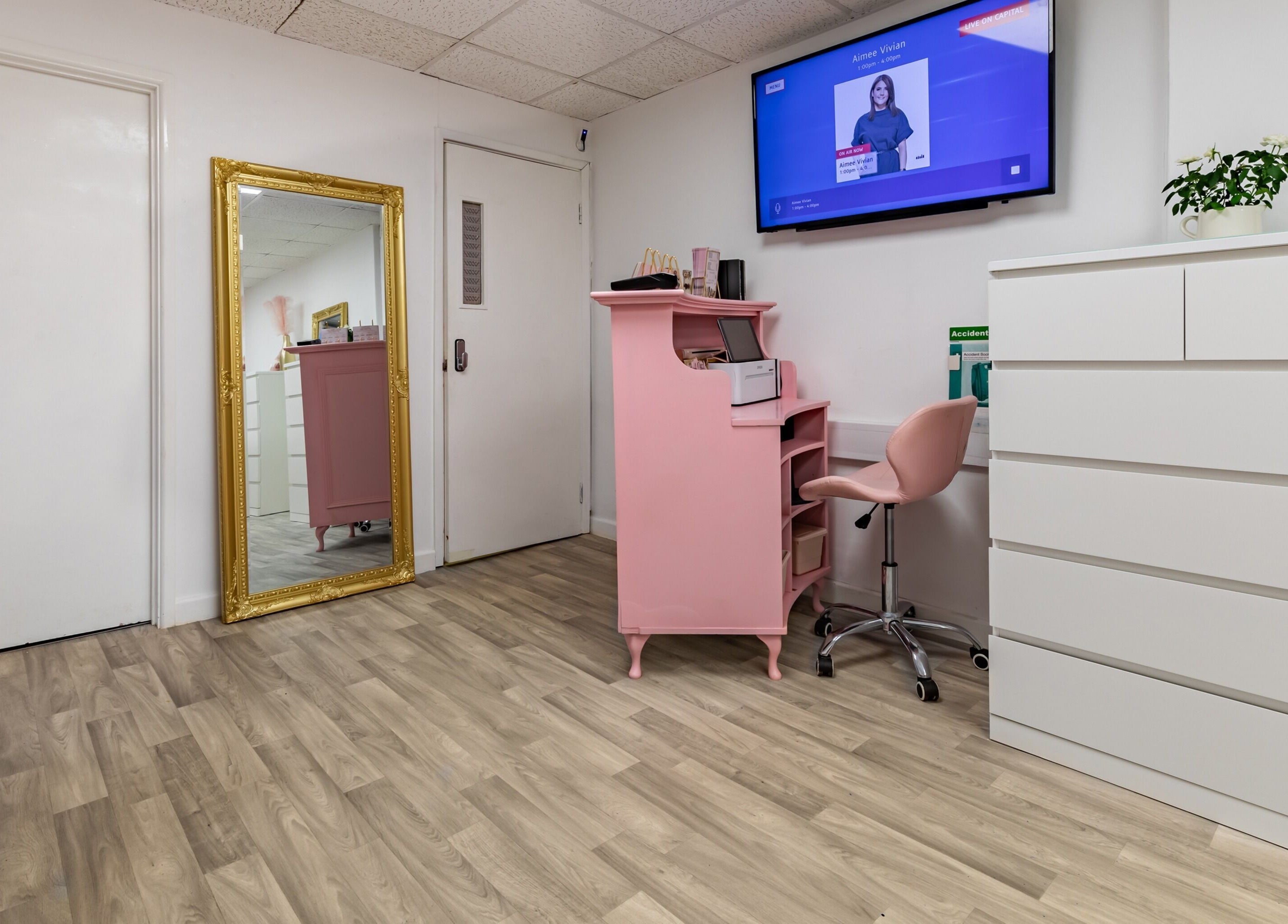Elegant interior of Luxe Beautè in Cardiff, Wales, GB, featuring a pink desk and gold-framed mirror.