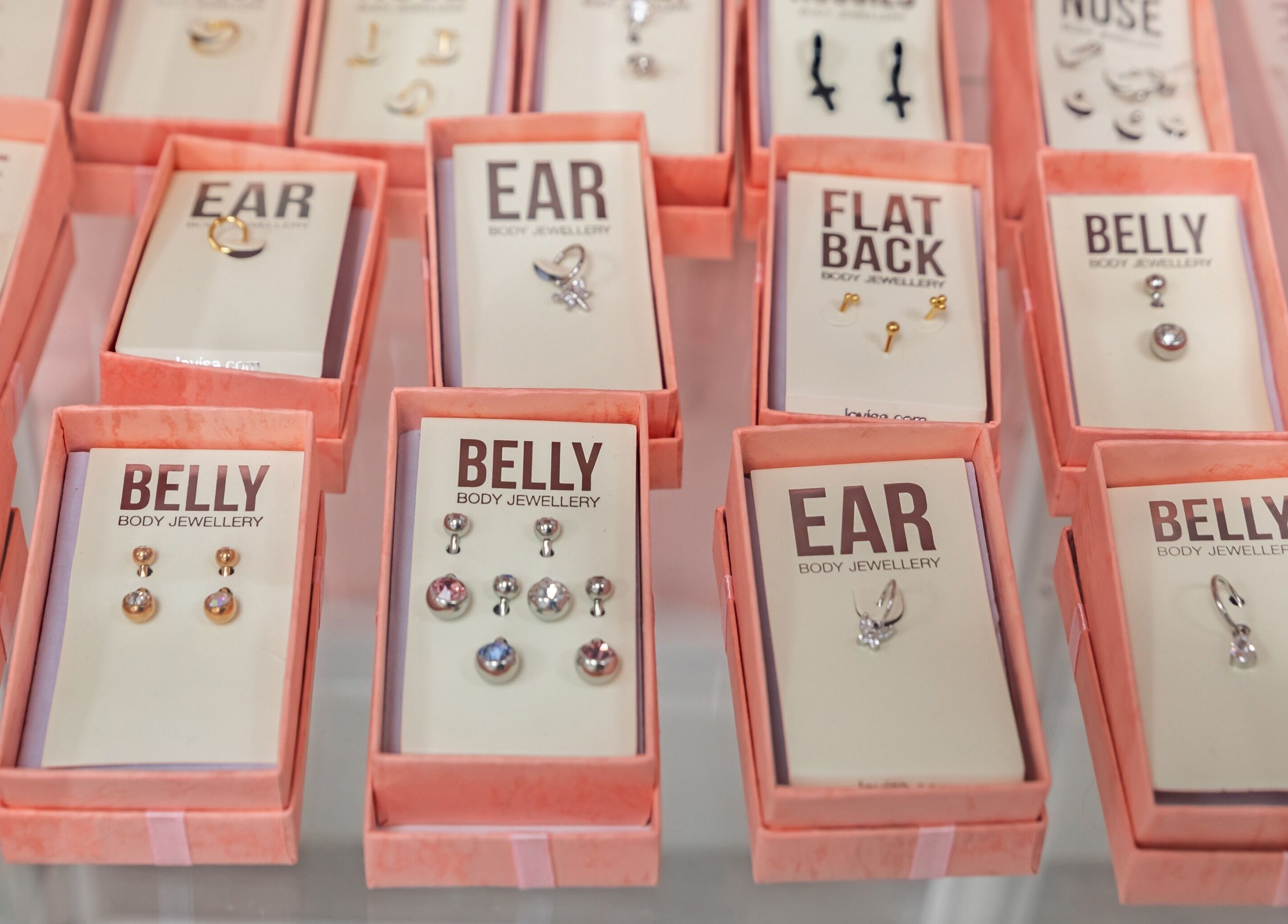 Assorted body jewellery boxes at Luxe Beautè, Cardiff, Wales, GB showcasing ear and belly designs.