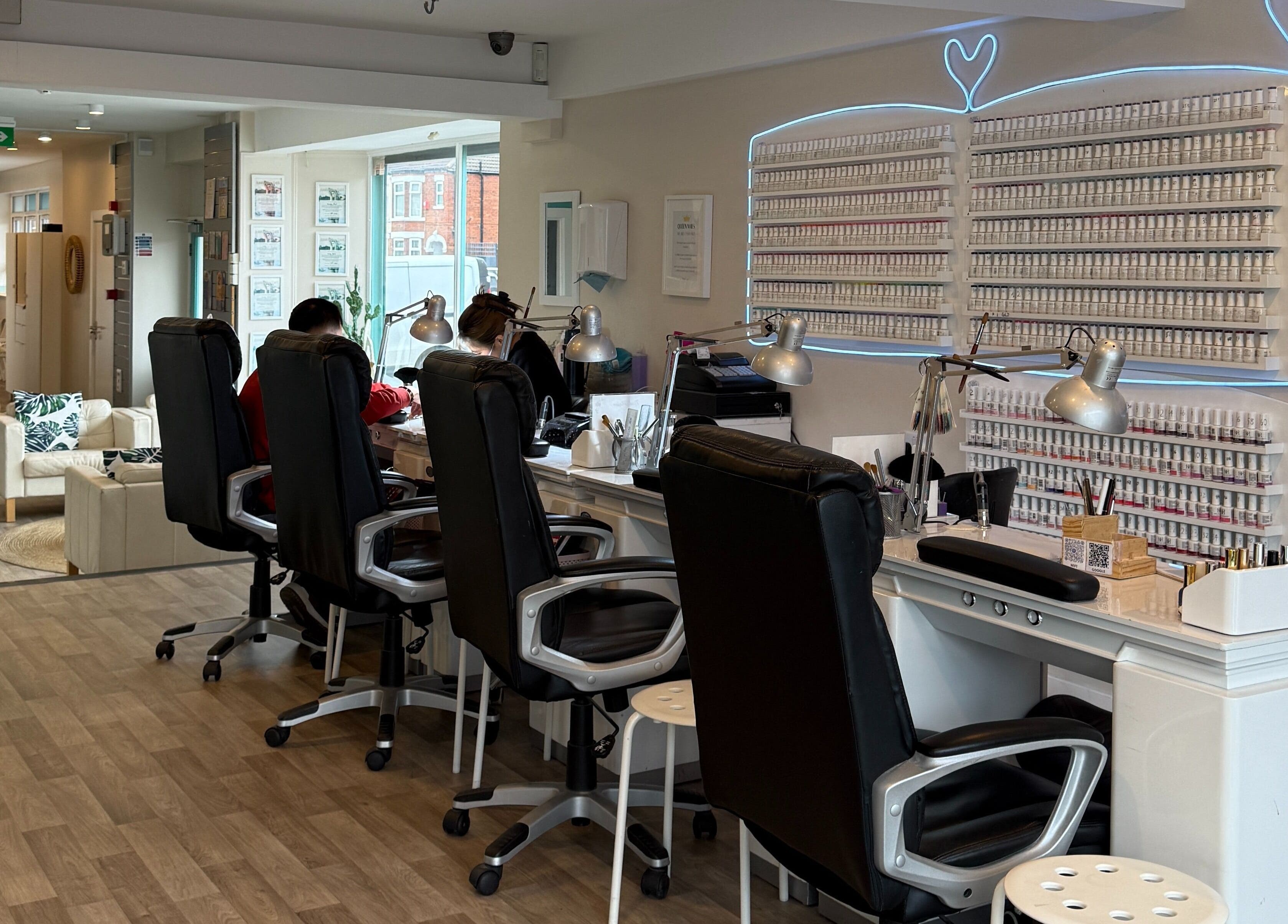 Modern interior of Queen Nails, Hull, England, GB, featuring nail stations and a vibrant polish display.
