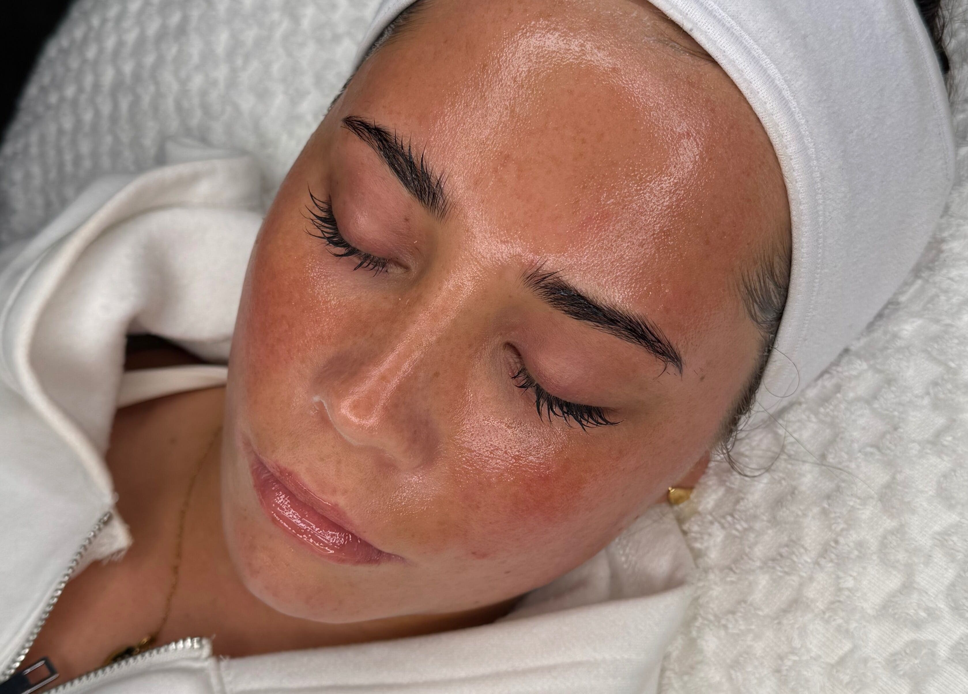 Woman receiving facial treatment at After Glow by Liv, Worsley, England, GB. Glowing skin after wellness session.