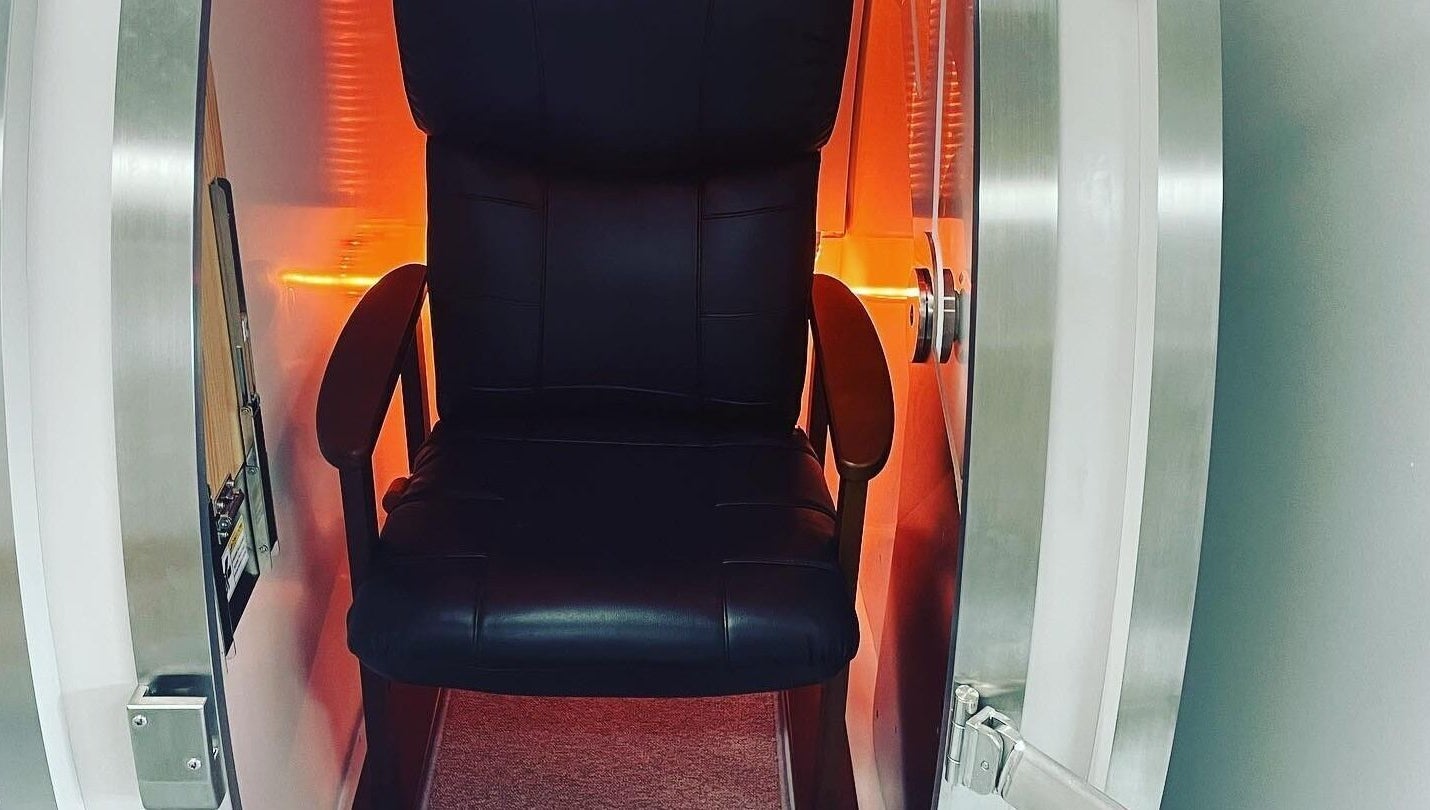 Hyperbaric O2 Health chamber in Bowen Hills, Queensland, AU with a black chair and orange lighting.