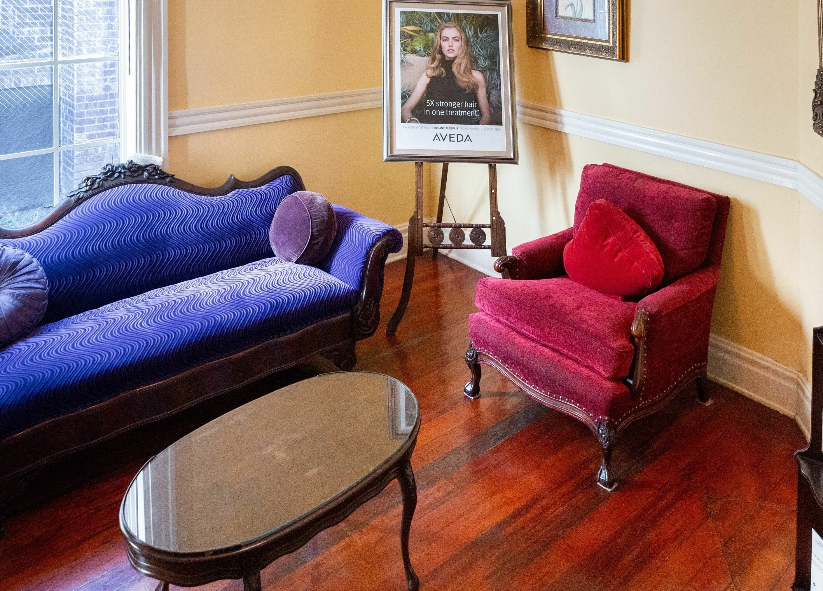 Chic waiting area at Salon Benardo, Fullerton, California, US, featuring a purple sofa and red armchair.
