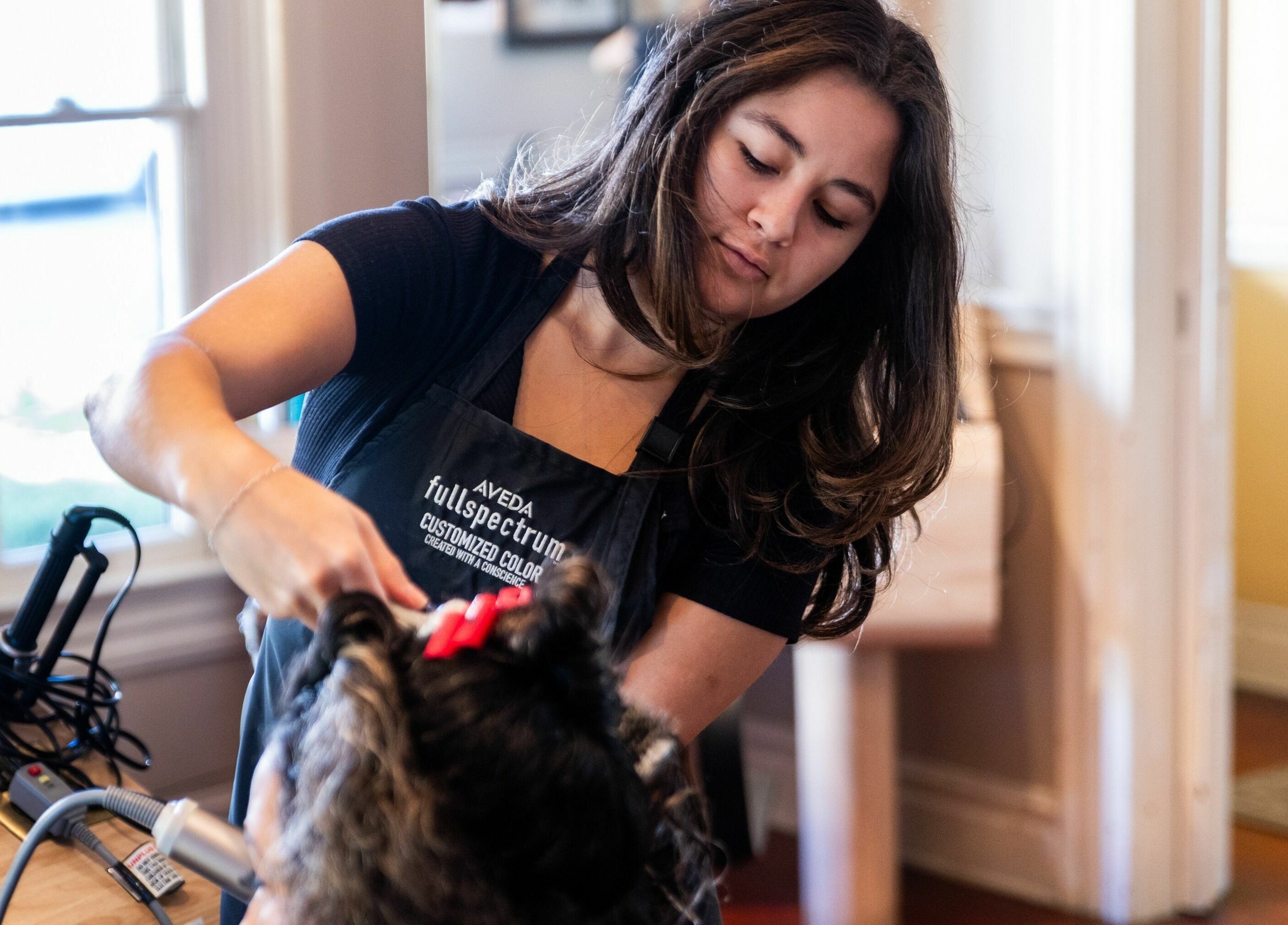 Stylist at Salon Benardo in Fullerton, California, US crafting curls with precision and care.