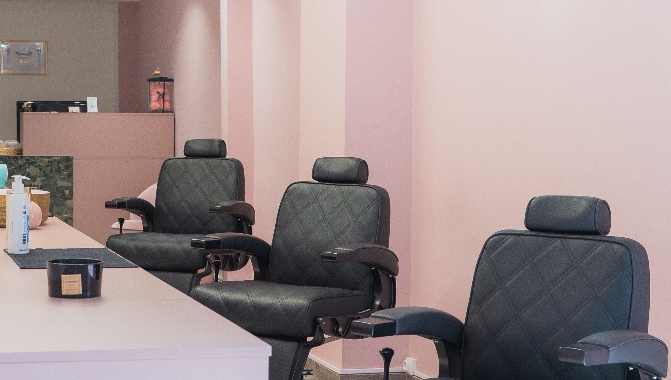 Σαλόνι ομορφιάς στο Aster The Beauty Brow Bar, Πειραιάς, GR με άνετες καρέκλες και ροζ τοίχους.