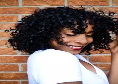 Smiling woman with curly hair at Natural Curly Haven, Toronto, Ontario, CA, embracing natural beauty.