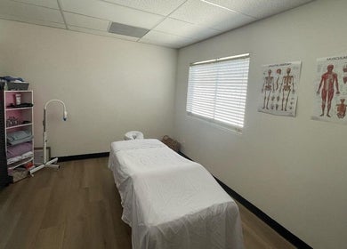 Massage therapy room at MMBW Industry, Ventura, California, US with treatment bed and anatomy charts.