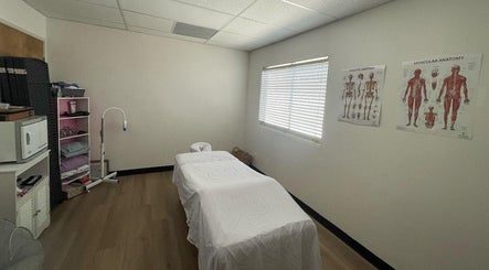 Massage therapy room at MMBW Industry, Ventura, California, US with treatment bed and anatomy charts.