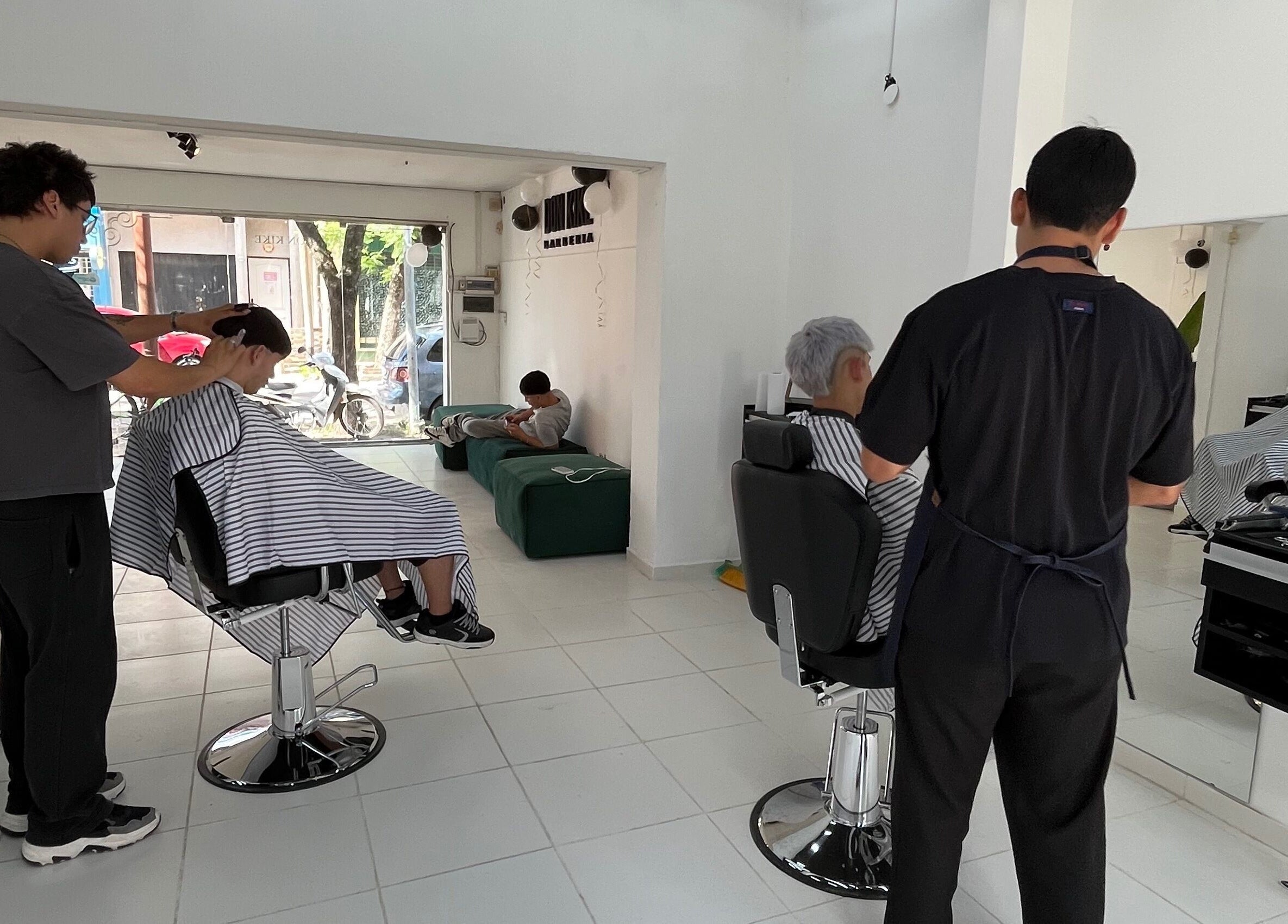 Interior de Don Kike Barberia - Gral. Rodríguez, Provincia De Buenos Aires, AR, con clientes recibiendo cortes de pelo.