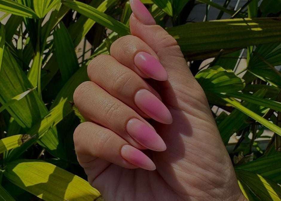 Pink ombre nails showcasing elegance at LAU’S BEAUTY, Bali, Bali, ID, against lush green leaves.