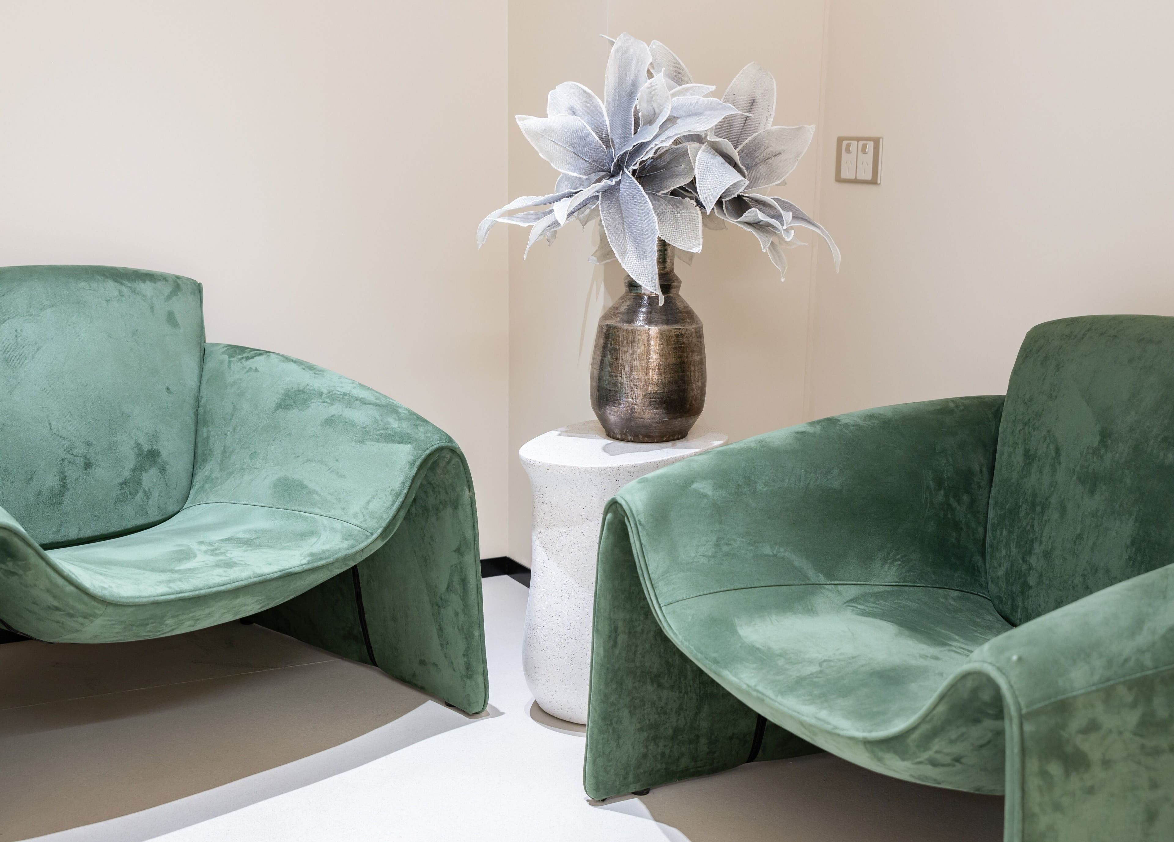 Elegant seating area at MEGUMI GLOBAL in Sydney, New South Wales, AU, featuring plush green chairs and decorative vase.