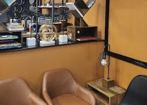 Comfortable seating at Masters Barbershop in Alpharetta, Georgia, US with stylish bookshelf and decor.