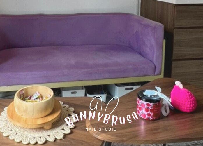 Relaxing lounge area at Bunny Brush Nail Studio, Petaling Jaya, Selangor, MY, showcasing a purple couch and tables.