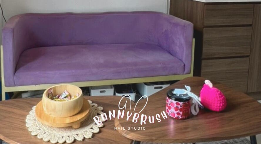 Relaxing lounge area at Bunny Brush Nail Studio, Petaling Jaya, Selangor, MY, showcasing a purple couch and tables.