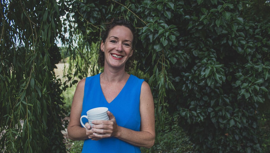 Smiling person holding a mug in lush garden at Amanda Smith Holistics - Framlingham, Framlingham, England, GB.