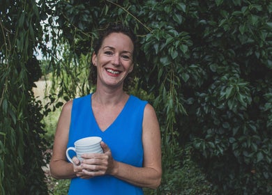 Smiling person holding a mug in lush garden at Amanda Smith Holistics - Framlingham, Framlingham, England, GB.