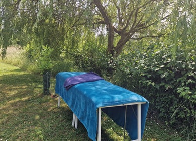Outdoor massage table at Amanda Smith Holistics - Framlingham, England, GB shaded by lush greenery.