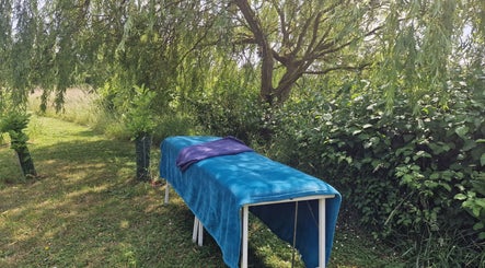 Outdoor massage table at Amanda Smith Holistics - Framlingham, England, GB shaded by lush greenery.