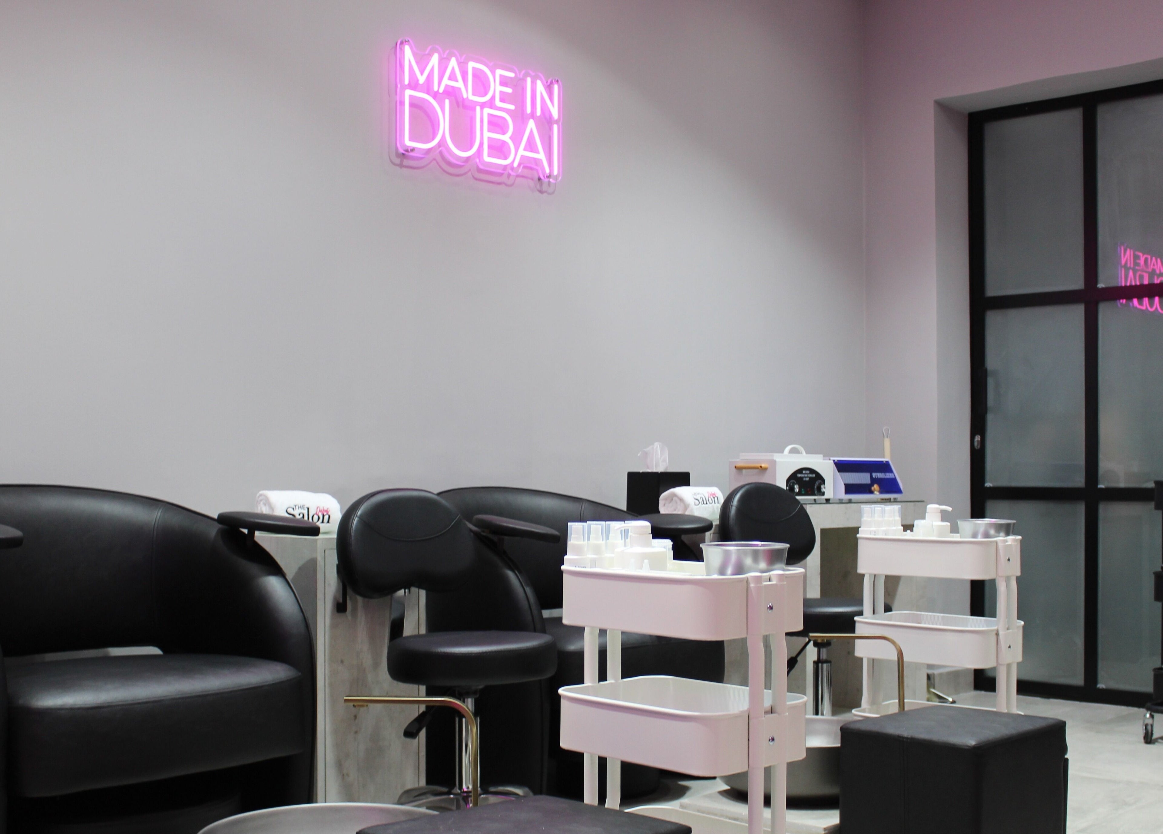 Modern salon interior at The Salon at Ocean View Hotel JBR, Dubai, AE, featuring stylish black seating and neon decor.