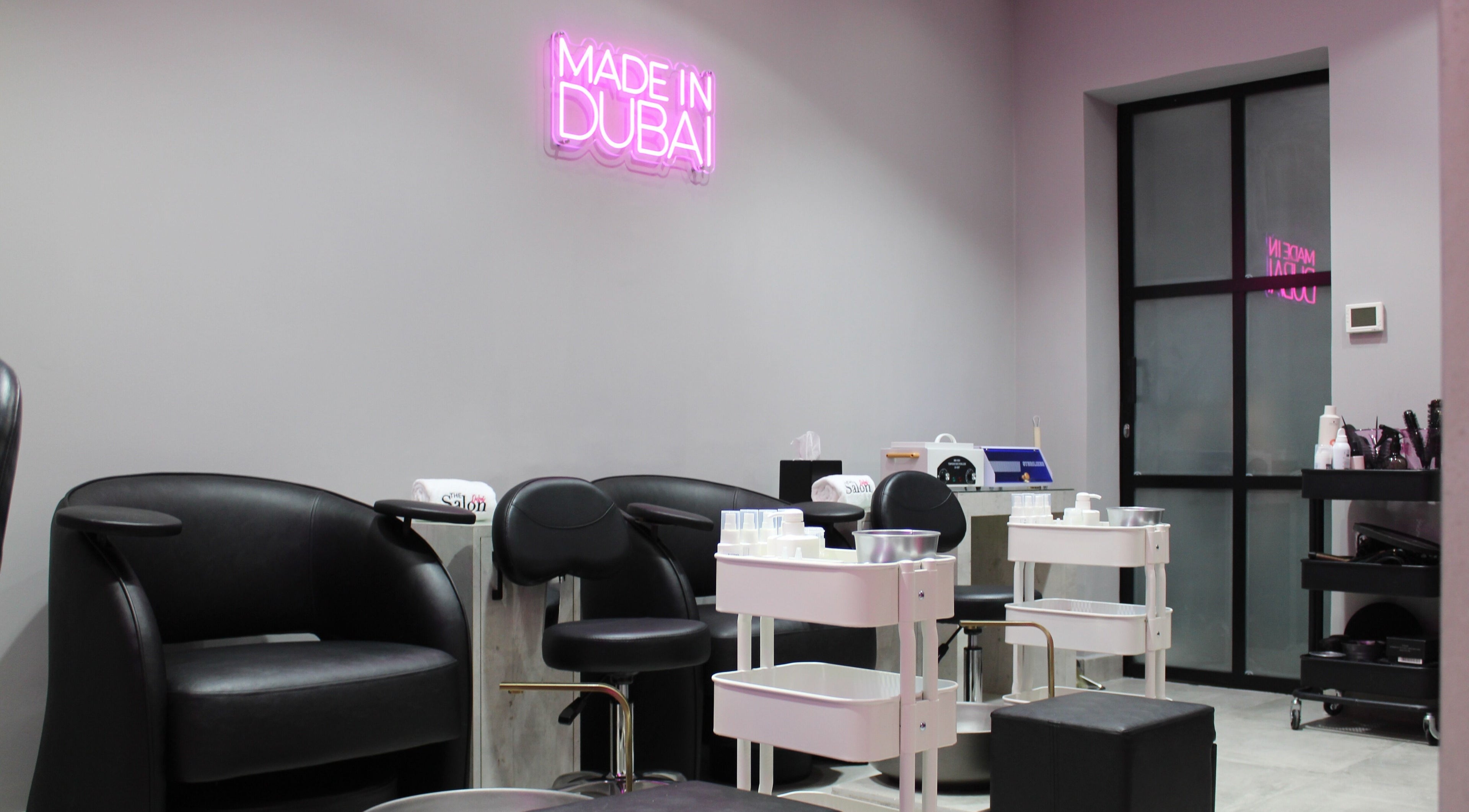 Modern salon interior at The Salon at Ocean View Hotel JBR, Dubai, AE, featuring stylish black seating and neon decor.