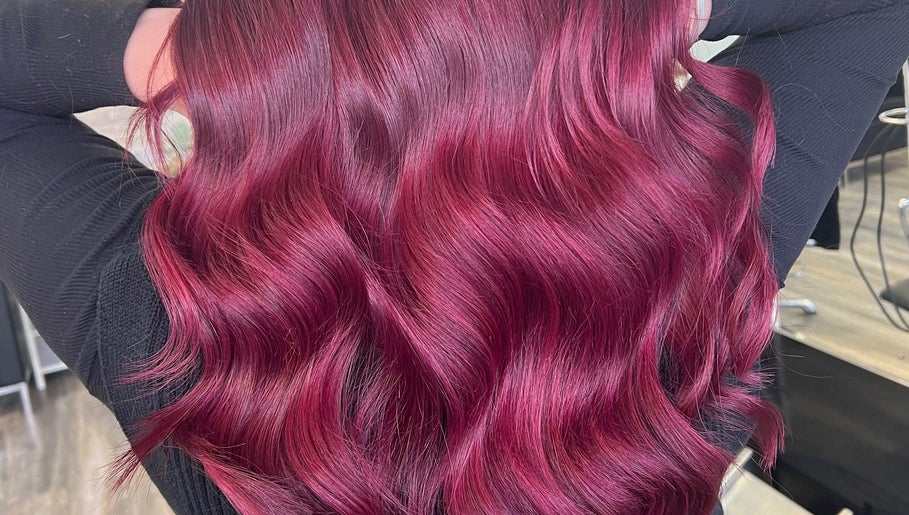 Vibrant crimson hair waves at Poppy Harrison Hair, Blackpool, England, GB showcasing rich color and shine.