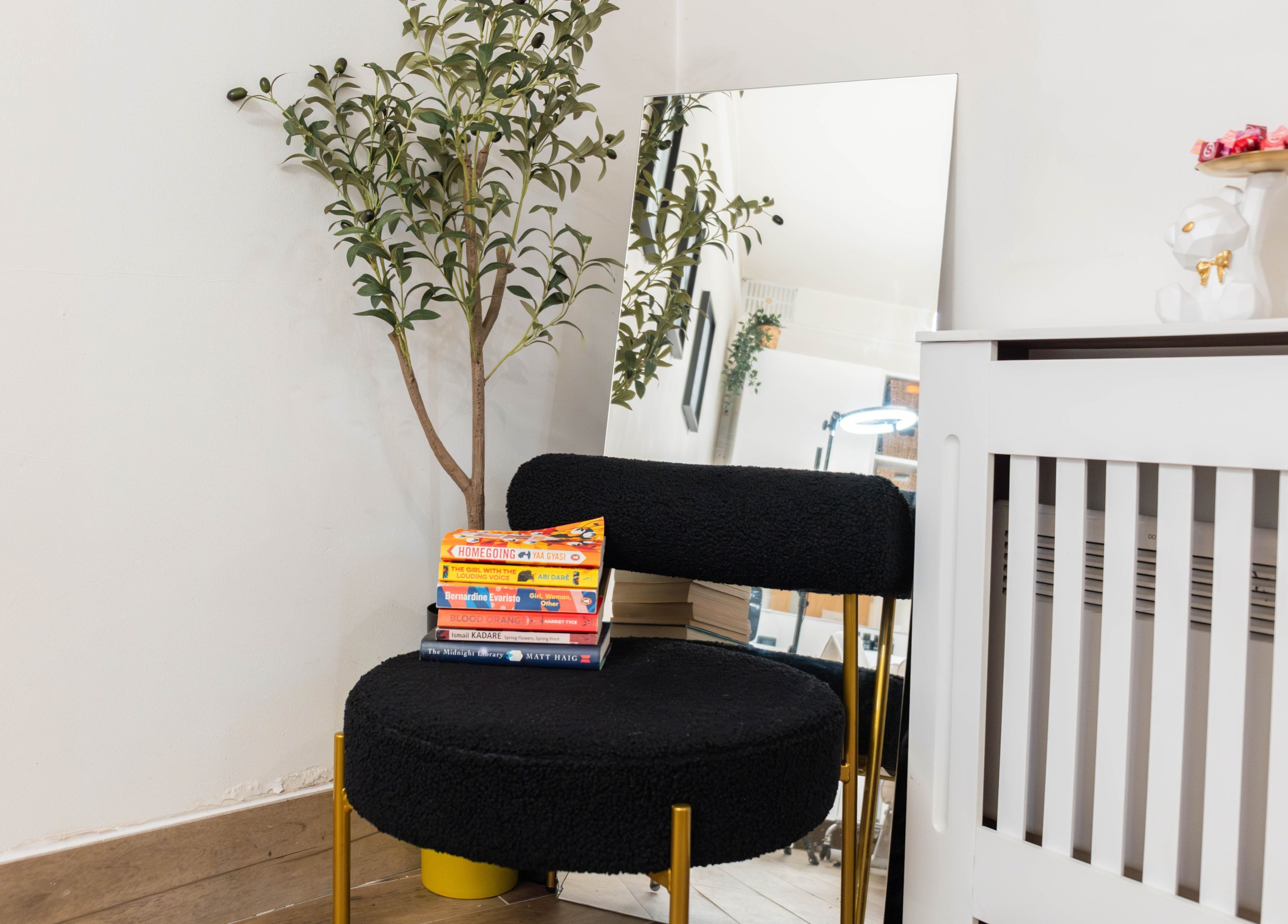 Chic corner at Jeta Brows, London, England, GB, with a black chair, books, and decor.