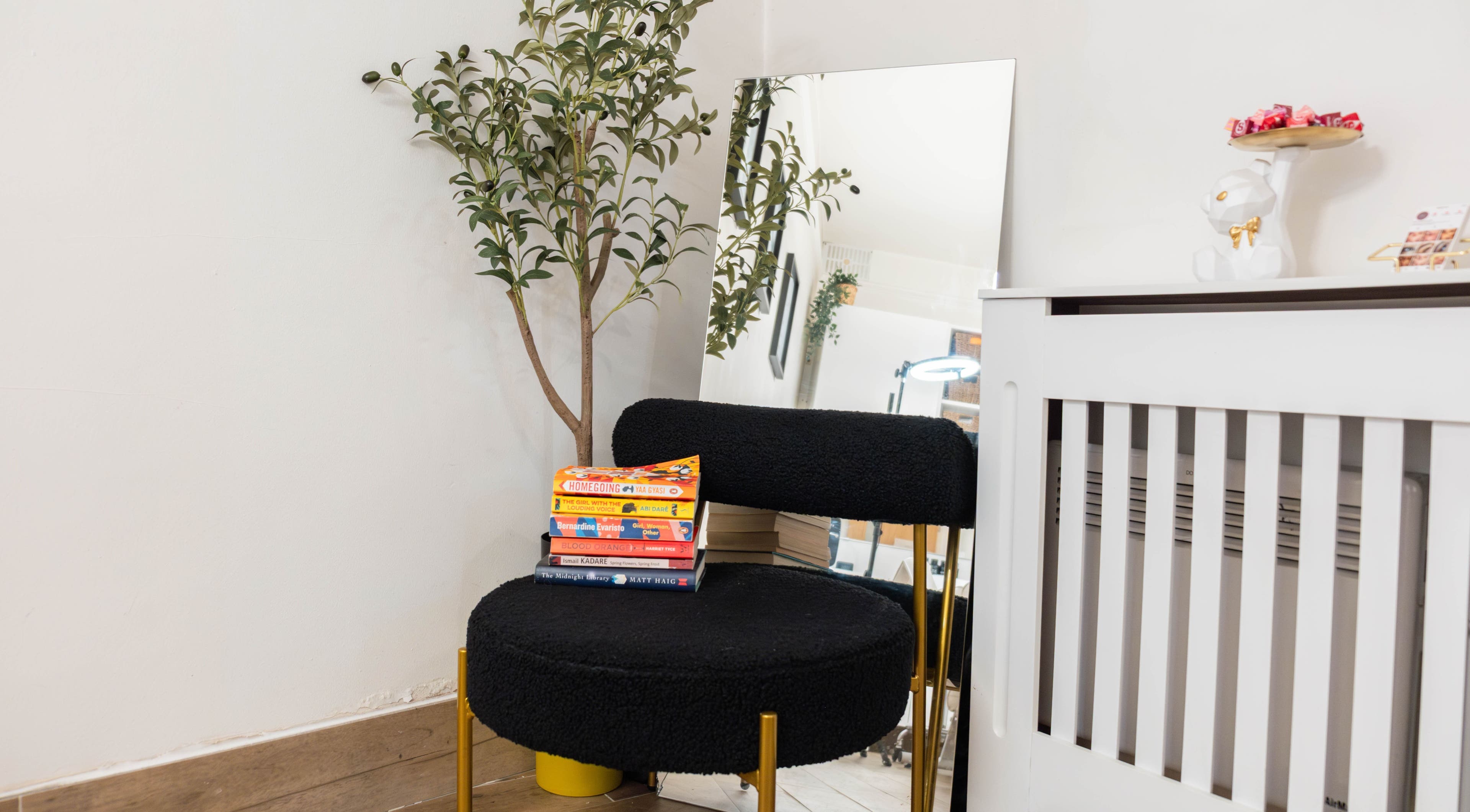 Chic corner at Jeta Brows, London, England, GB, with a black chair, books, and decor.