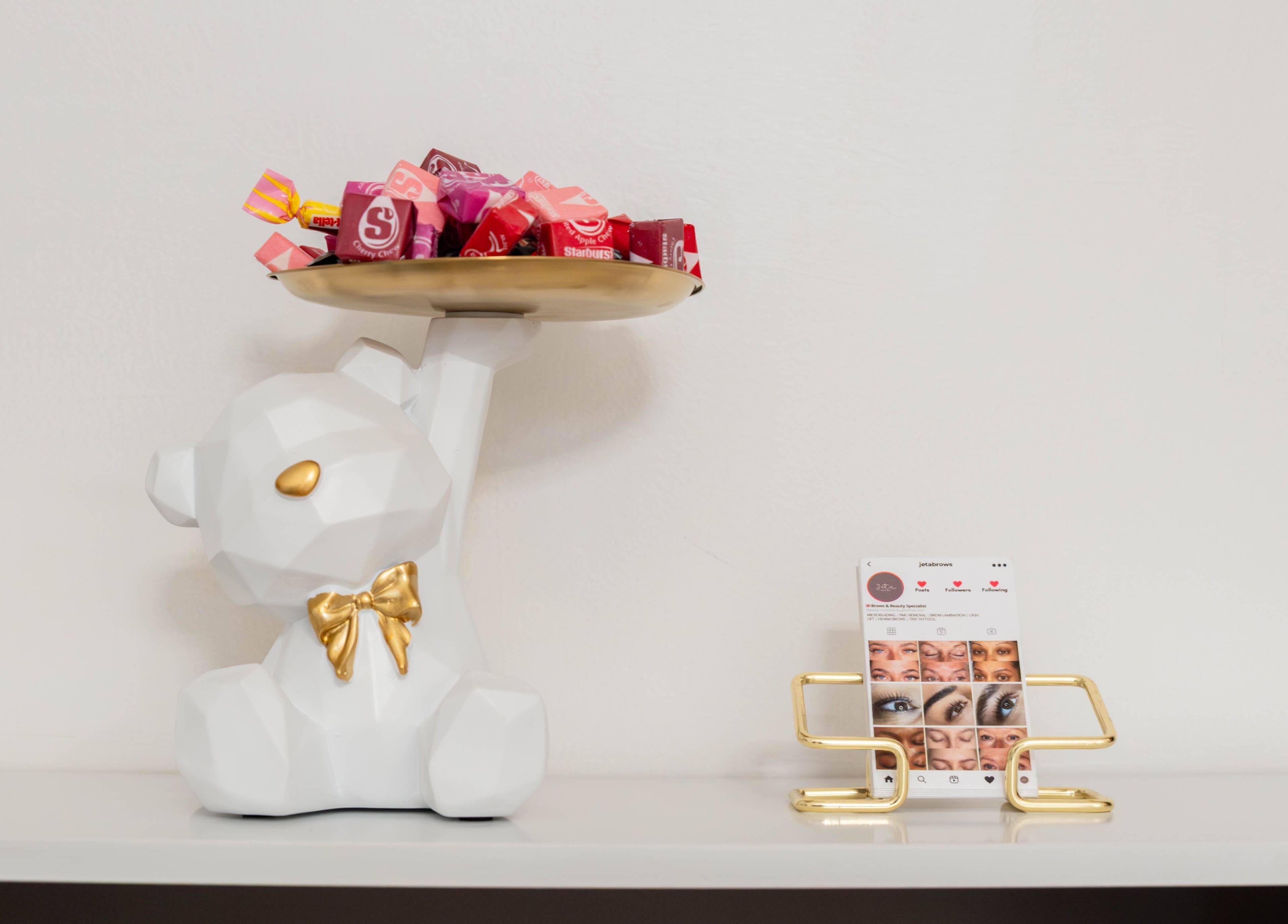 Chic bear statue with candy at Jeta Brows, London, England, GB. Sleek card holder adds stylish touch.
