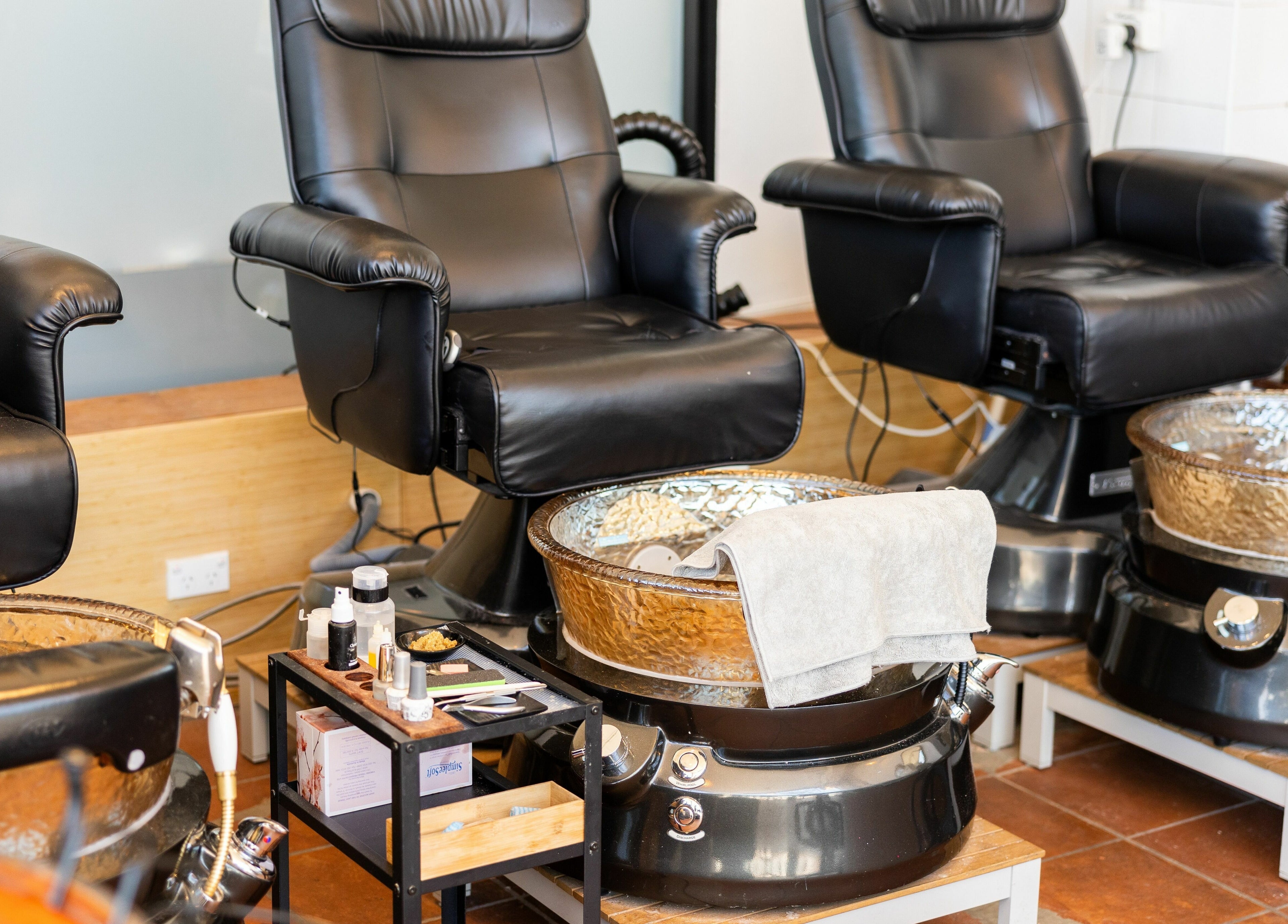 Luxurious pedicure stations at La Coeur - Rosebery in Rosebery, New South Wales, AU. Comfortable black chairs and spa bowls.