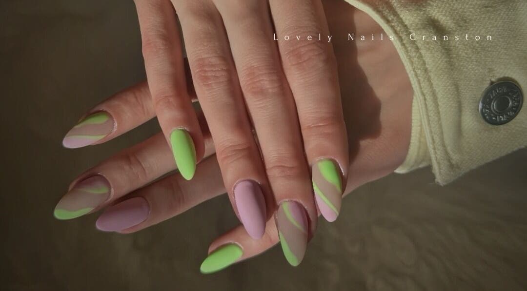 Colorful nail art with green and purple designs at Lovely Nails Spa, Cranston, Rhode Island, US.