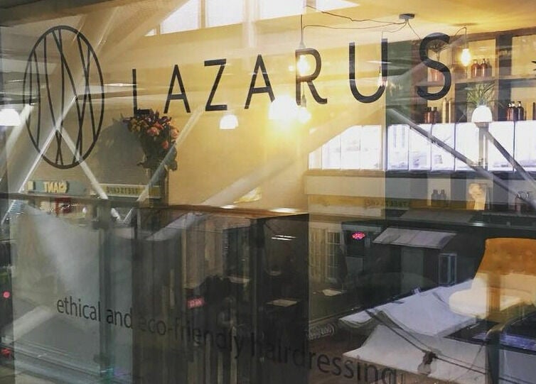 Lazarus Hair salon window in Brighton, England, GB. Reflective glass showcases eco-friendly ethos.
