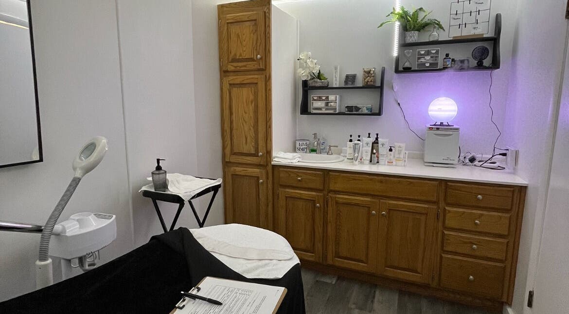 Calm treatment room at Timeless Beauty Bar LLC, Chillicothe, Missouri, US, showcasing wooden cabinets and spa equipment.