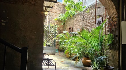 Enchanting courtyard at Sirena's Psychic Parleure, New Orleans, Louisiana, US, with lush plants and rustic brick walls.