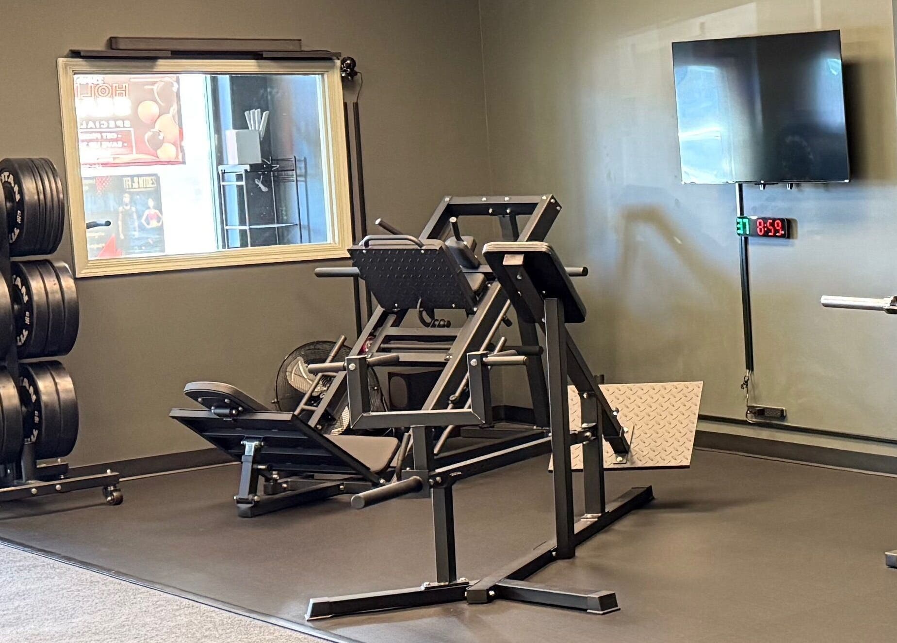 Fitness equipment at TNT Personal Training Studio in Duluth, Georgia, US, featuring weights and a leg press machine.