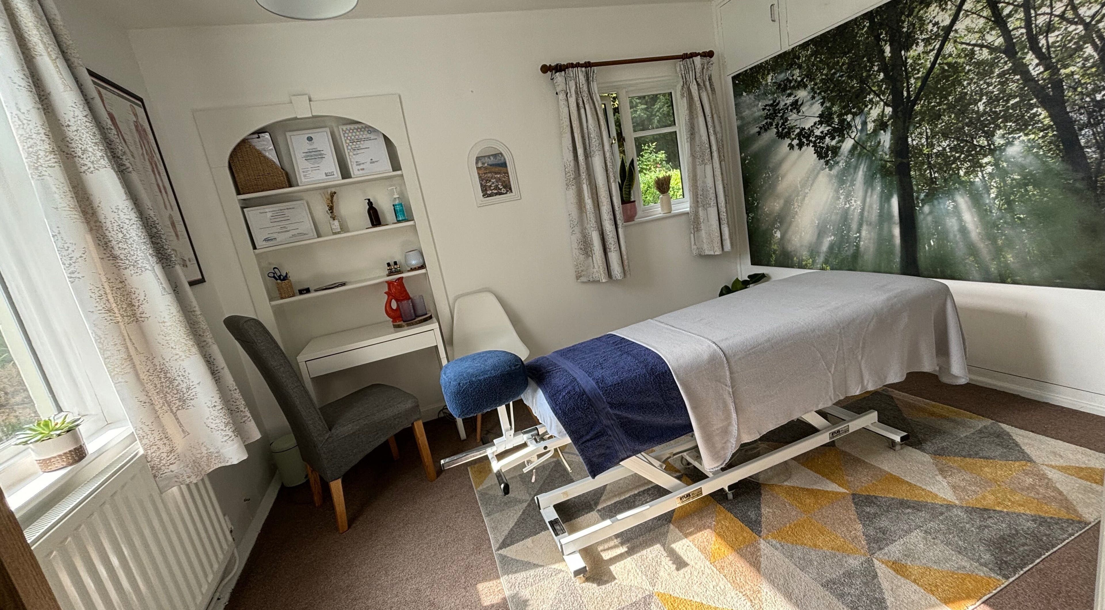 Serene massage room at Rooted Wellness in Kineton, England, GB featuring a therapy bed and forest mural.
