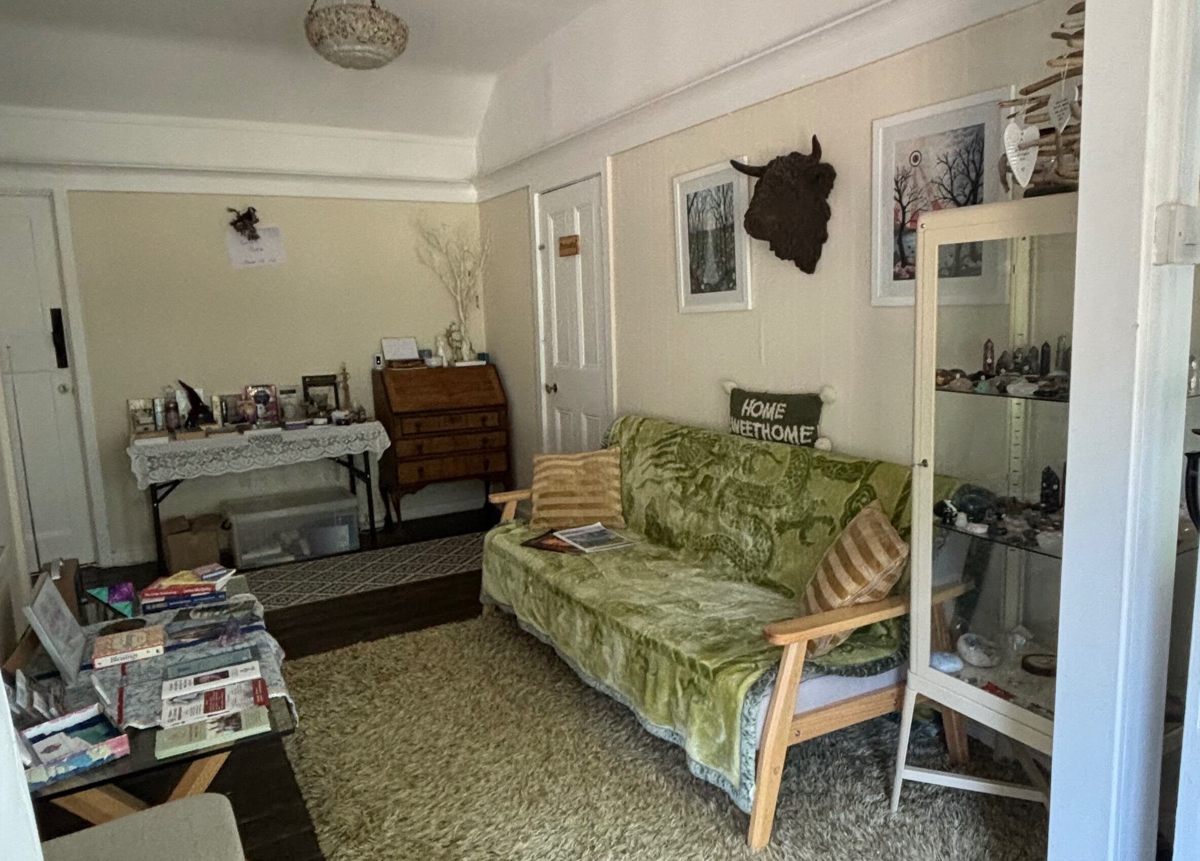 Cozy lounge area at Rooted Wellness, Kineton, England, GB, featuring a green sofa and eclectic decor.