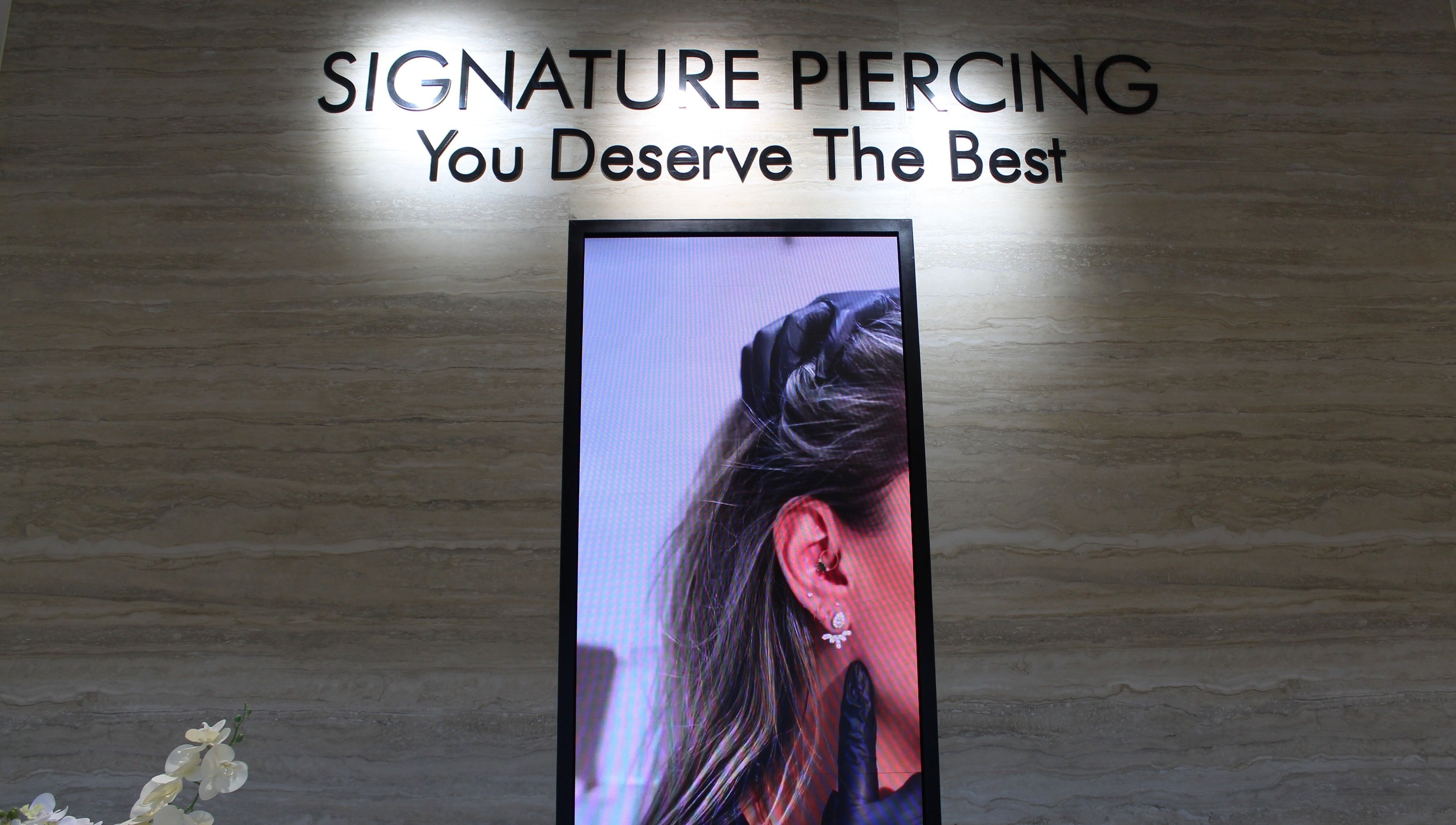 Interior of Signature Piercing, Abu Dhabi, AE showcasing a stylish ear piercing advertisement.