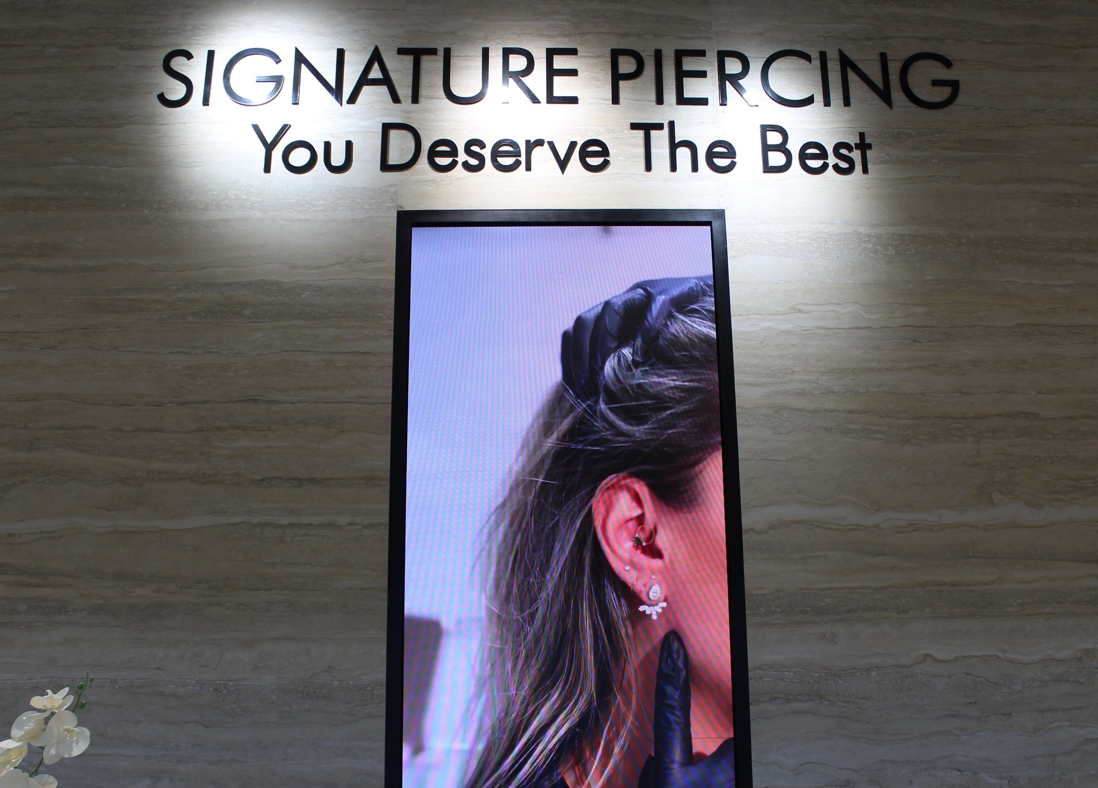 Interior of Signature Piercing, Abu Dhabi, AE showcasing a stylish ear piercing advertisement.
