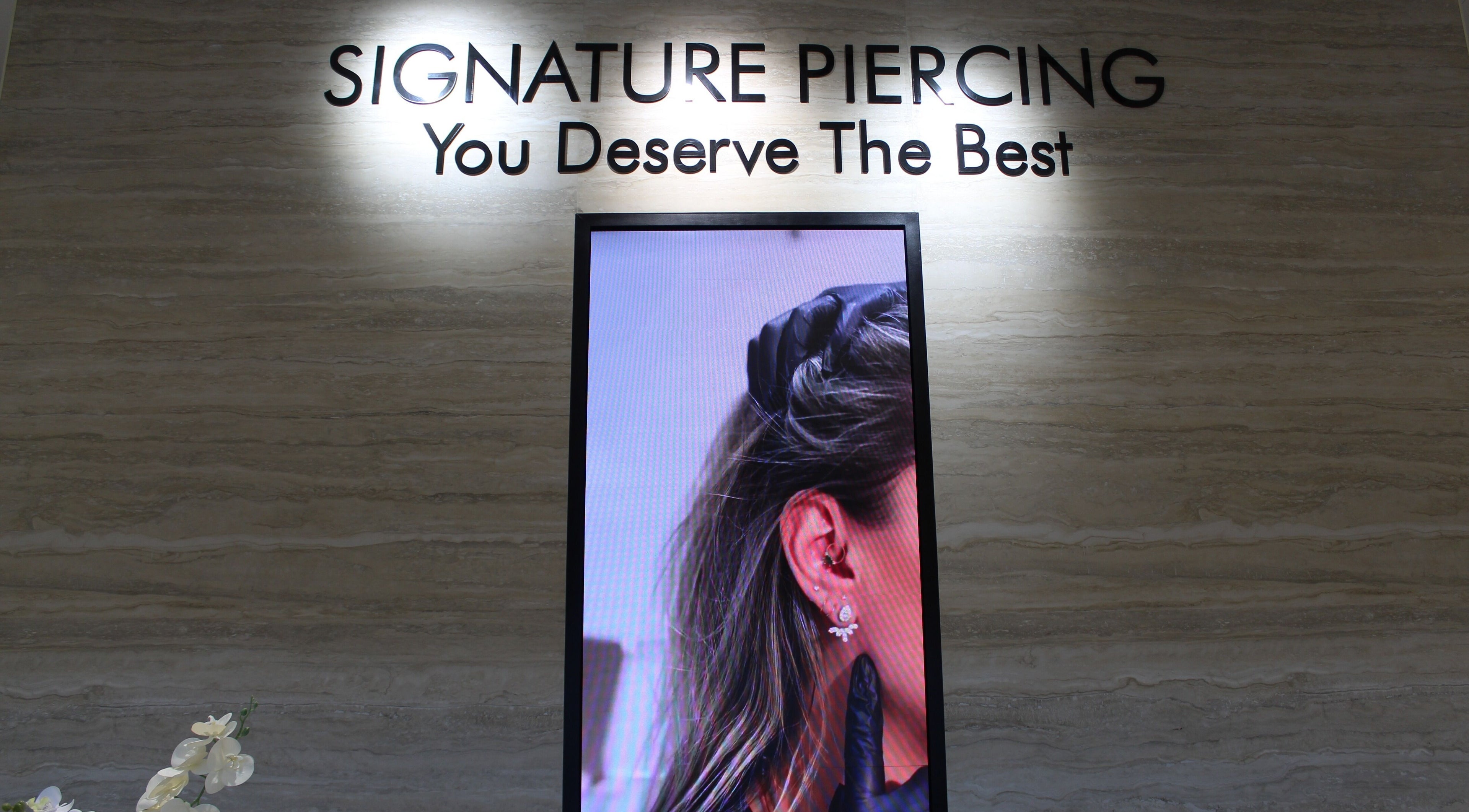 Interior of Signature Piercing, Abu Dhabi, AE showcasing a stylish ear piercing advertisement.