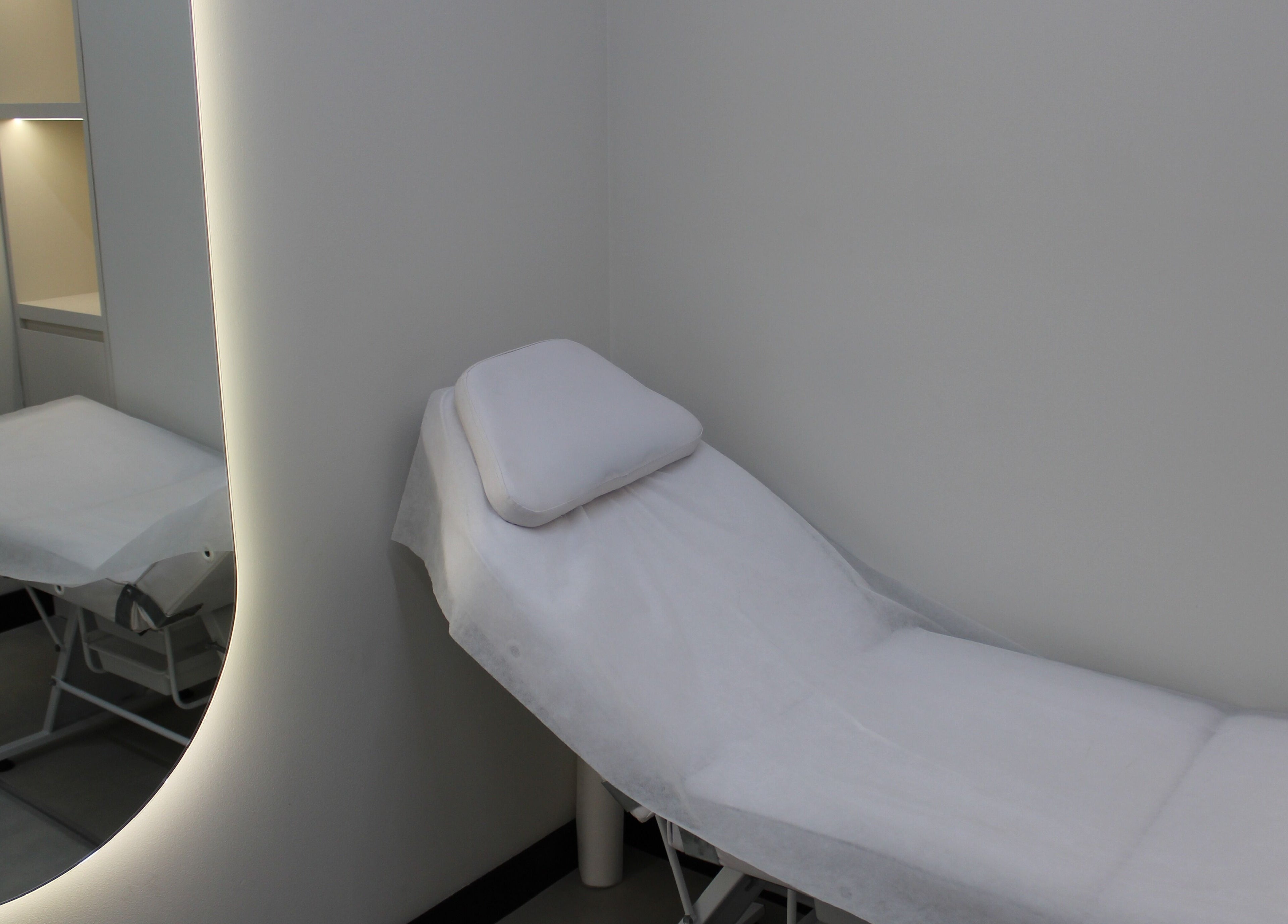 Modern treatment room at Signature Piercing, Abu Dhabi, AE, featuring a sleek bed and tranquil lighting.