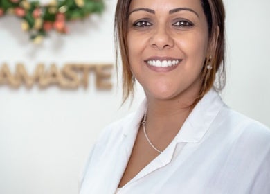 Profissional sorridente no Natura Studio em São Brás De Alportel, Faro, PT, com decoração acolhedora ao fundo.
