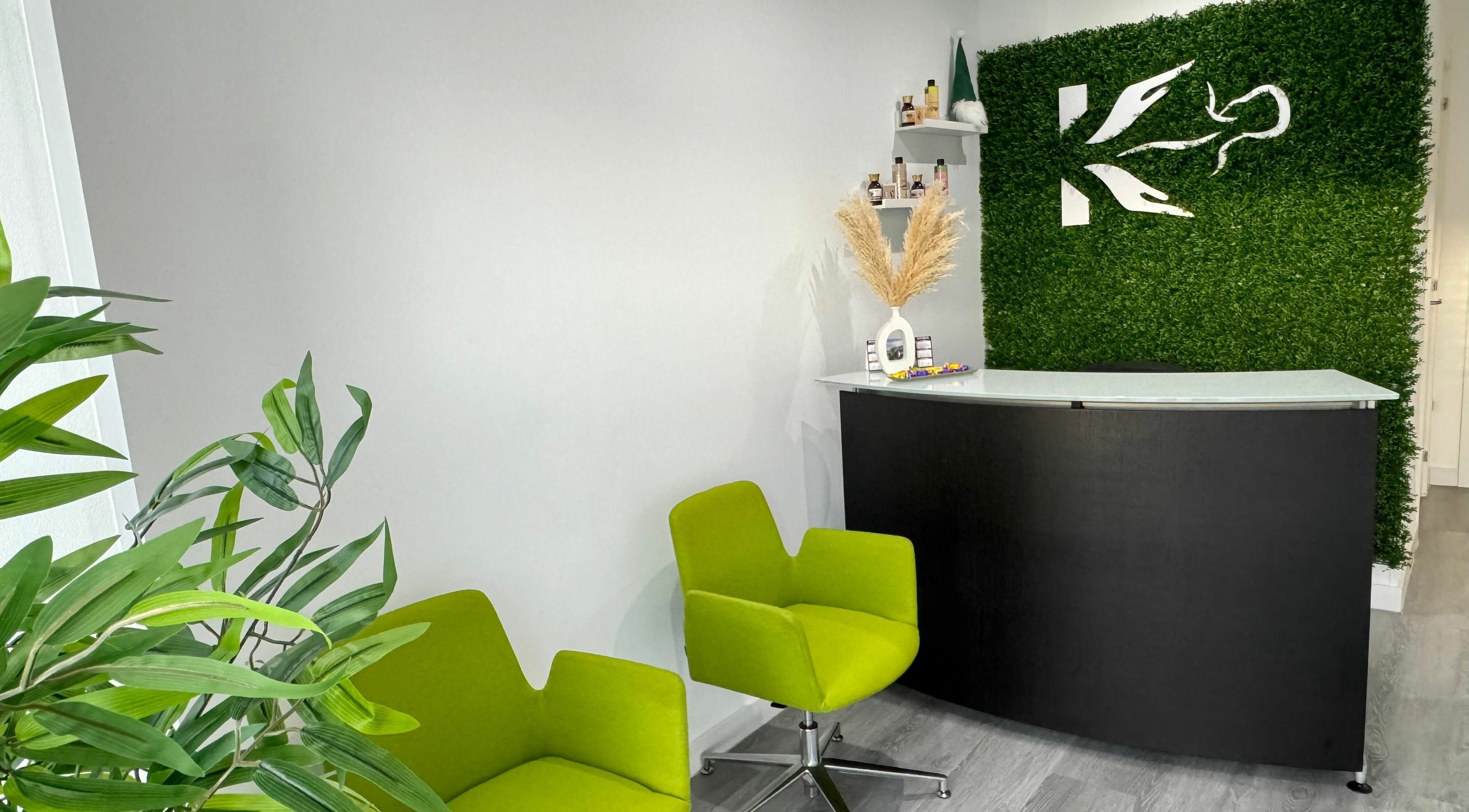 Área de recepción moderna en Fisiokalma, Suances, Cantabria, ES con sillas verdes y decoración natural.