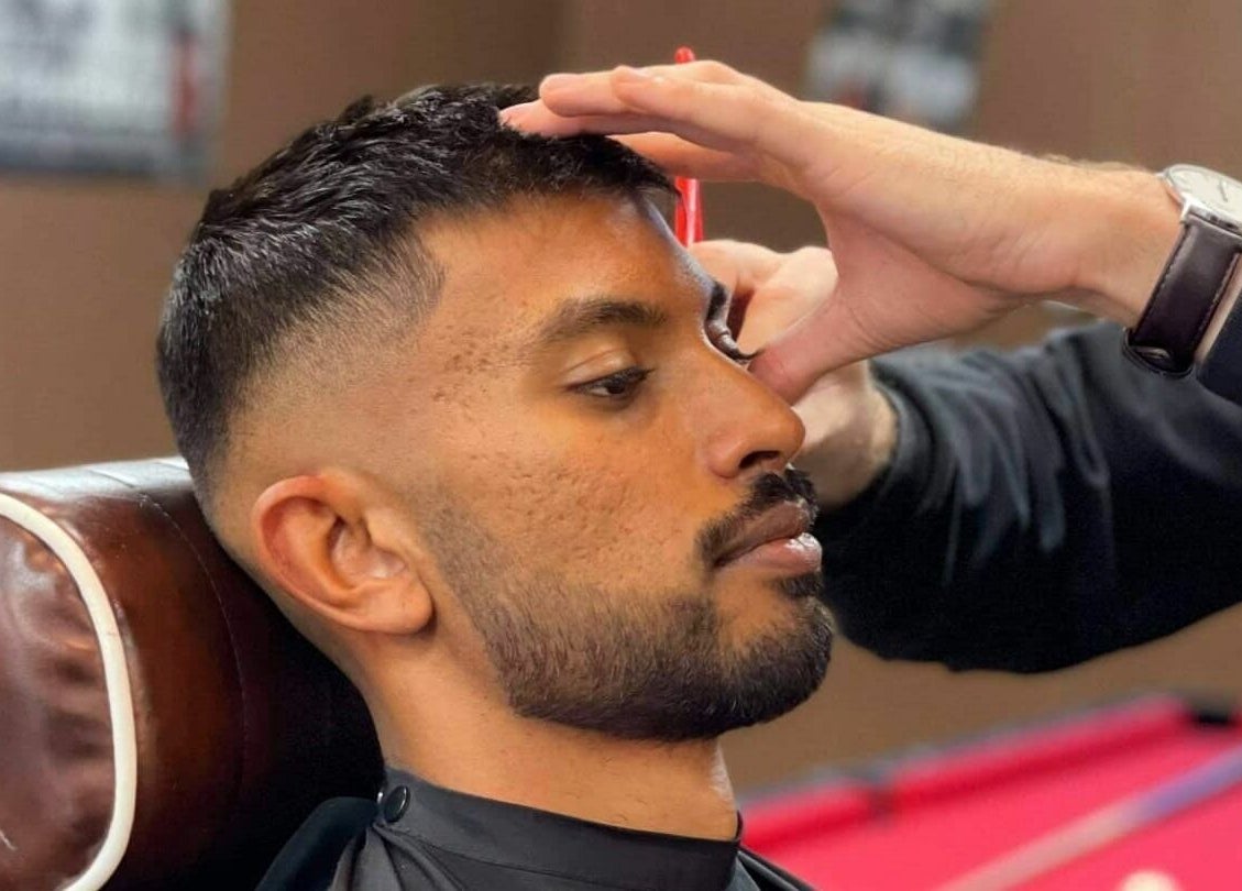 Barber expertly trims client's hair at Carlisle St in Balaclava, Melbourne, Victoria, AU. Opposite Woolworths.