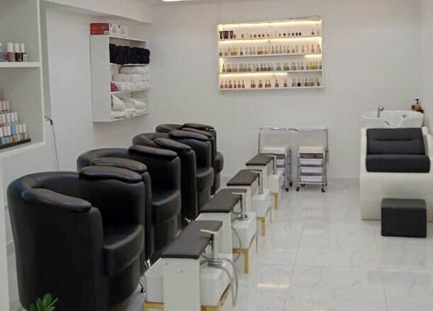 Chic nail salon area at Glamour Haven Beauty Center, Abu Dhabi, Abu Dhabi, AE, with black chairs and nail polish display.