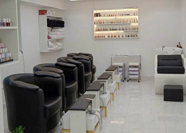 Chic nail salon area at Glamour Haven Beauty Center, Abu Dhabi, Abu Dhabi, AE, with black chairs and nail polish display.