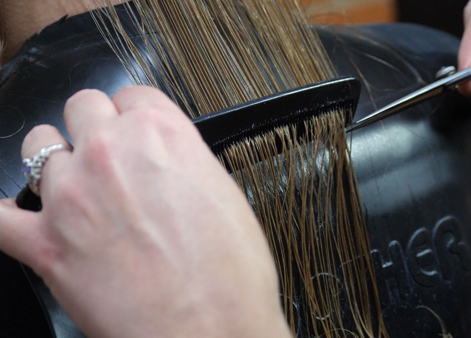 A stylist expertly trims hair at Alice Capriotti in Lavenham, England, GB, showcasing precise cutting technique.