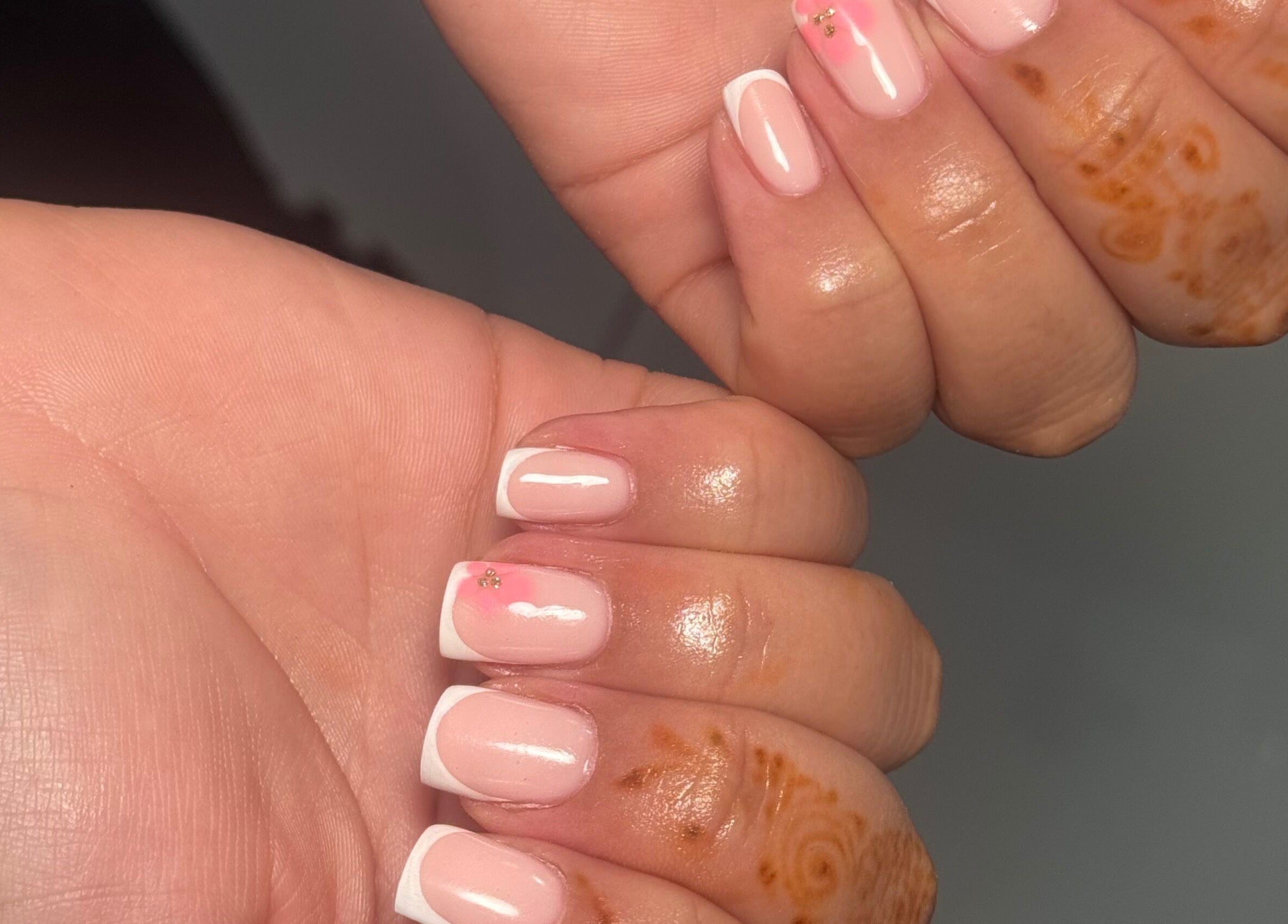 Chic pink and white French manicure at Biabbarr, Cardiff, Wales, GB. A touch of floral nail art enhances beauty.