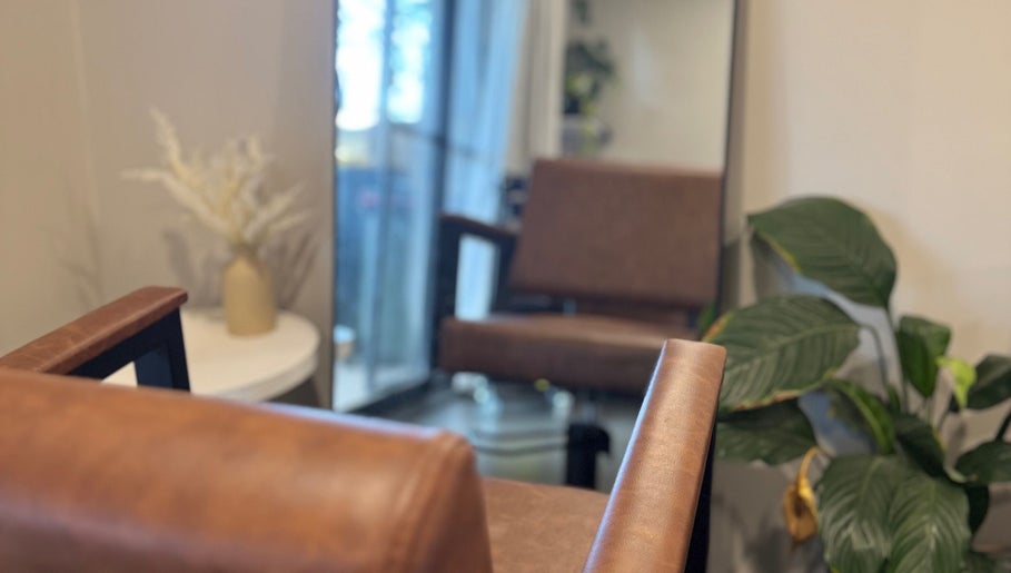 Cozy salon area at Hair by Jaz, Catalina, New South Wales, AU, featuring a leather chair and potted plant.
