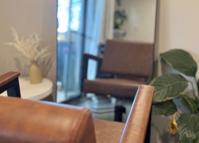 Cozy salon area at Hair by Jaz, Catalina, New South Wales, AU, featuring a leather chair and potted plant.