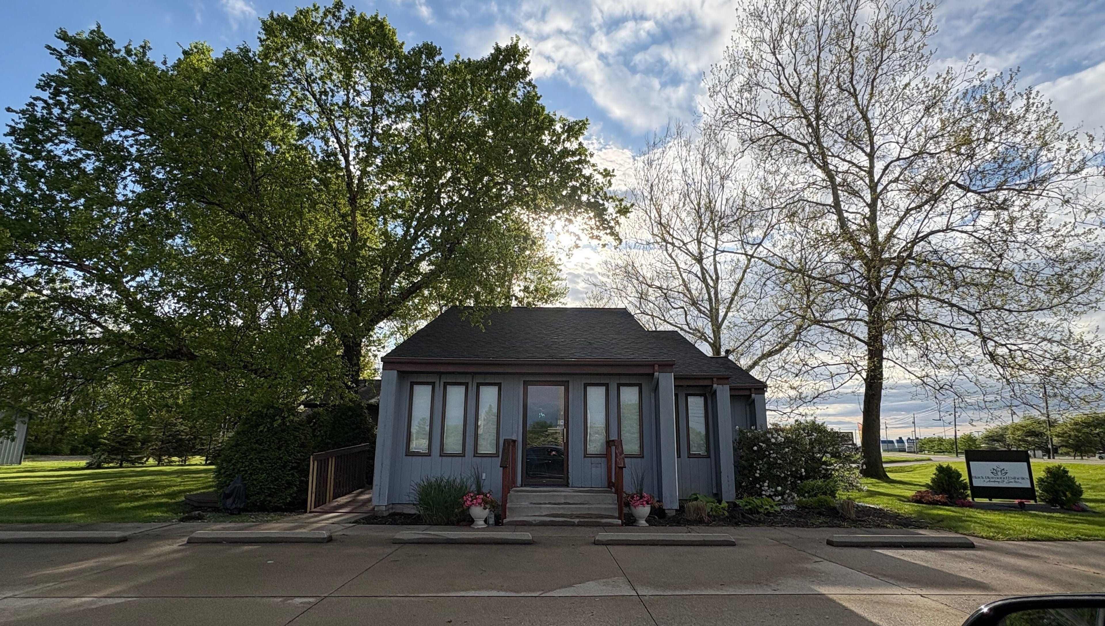 Charming facade of Enchanted Beauty Haven in Muncie, Indiana, US with lush greenery and a bright sky.