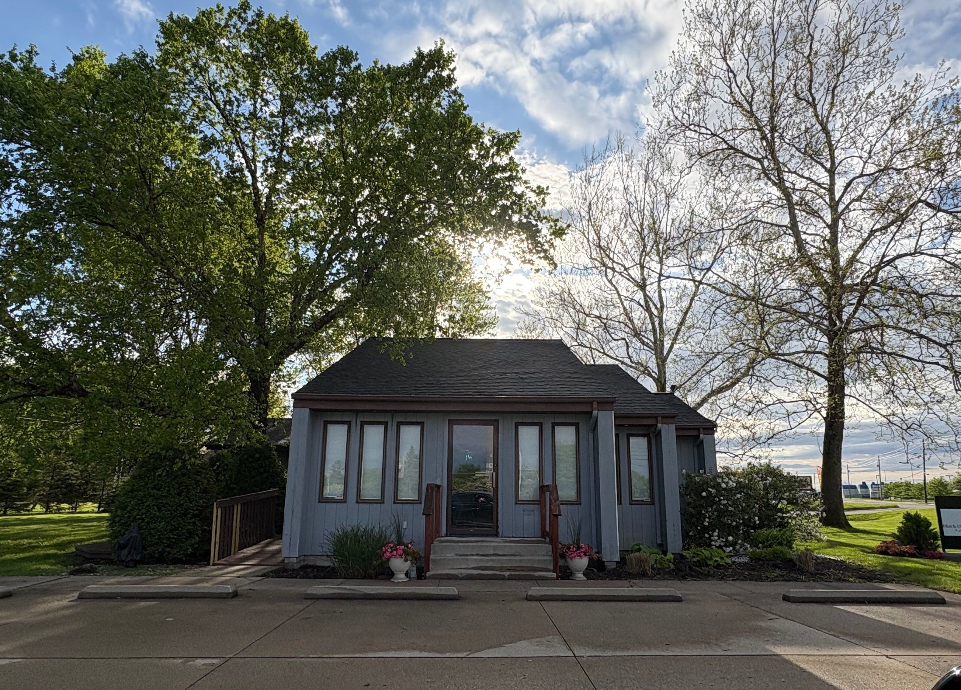 Charming facade of Enchanted Beauty Haven in Muncie, Indiana, US with lush greenery and a bright sky.